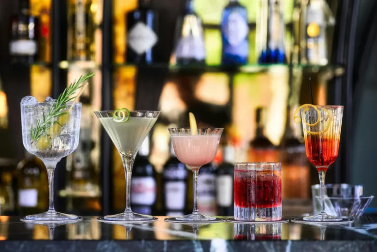 Nhiều ly cocktail khác nhau về màu sắc và dáng ly xếp cạnh nhau trên mặt quầy bar