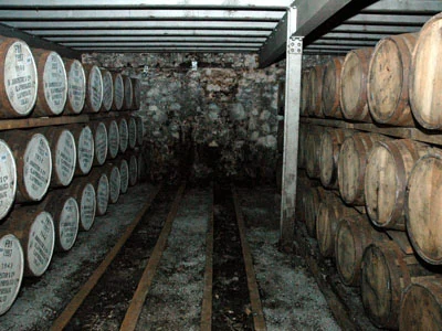 Kho ủ dunnage của nhà máy Laphroaig xếp đầy thùng ủ whisky, sàn đất và tường đá đặc trưng