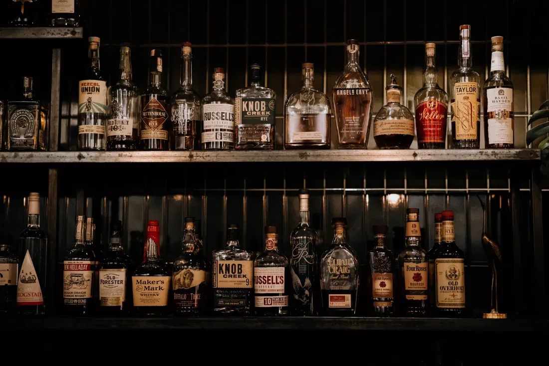 Kệ bar xếp đầy nhiều chai whisky đủ loại