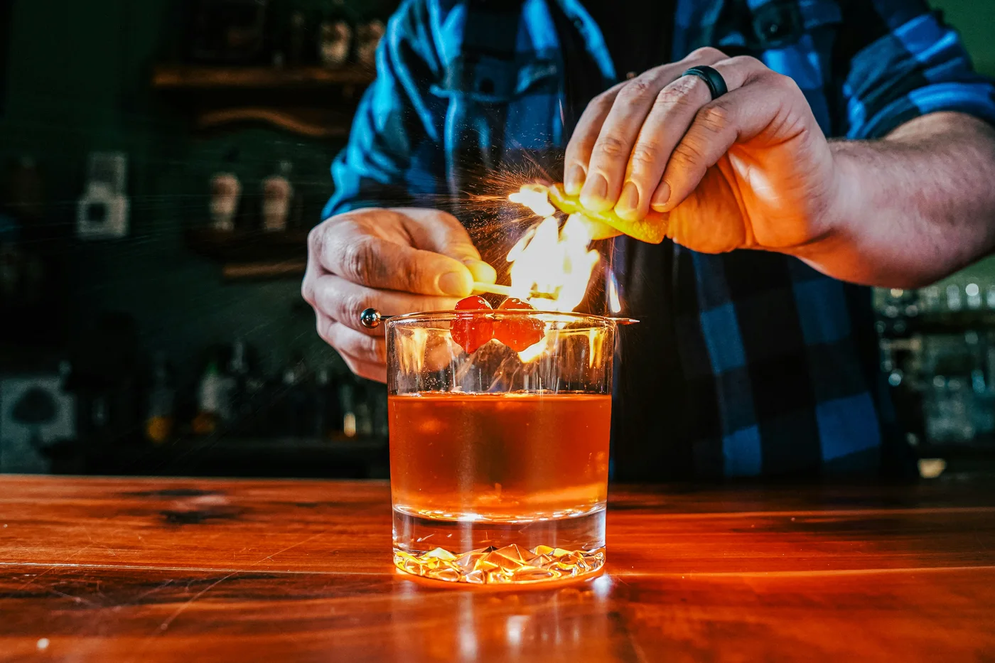 Người pha chế đốt tinh dầu vỏ cam bằng que diêm trên mặt ly Old Fashioned