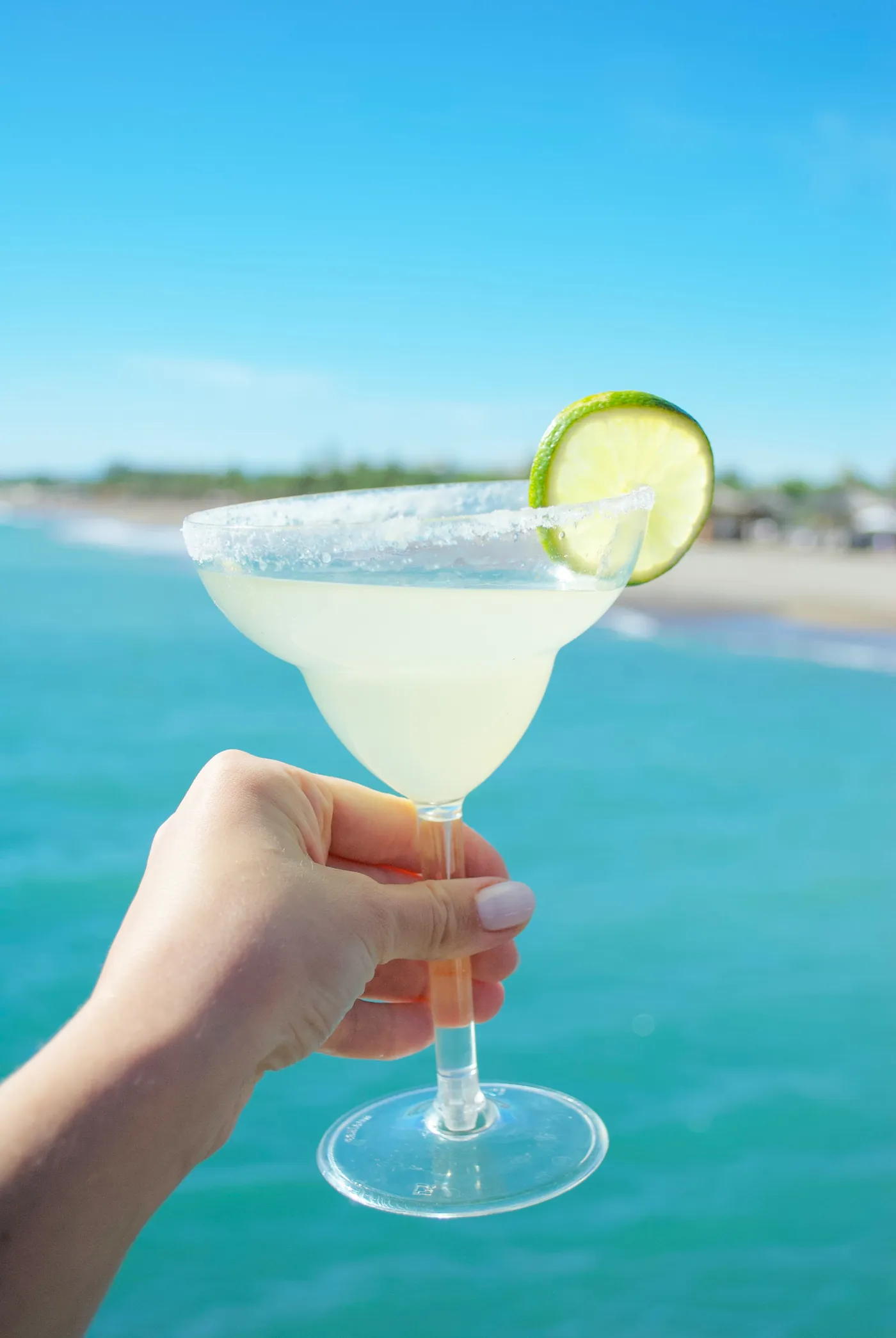 Ly Margarita viền muối, chất lỏng đục mờ, đang được cầm ngoài trời