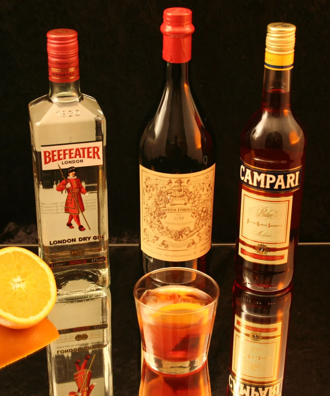 Ly Negroni đặt cạnh chai gin, chai Campari và chai vermouth ngọt
